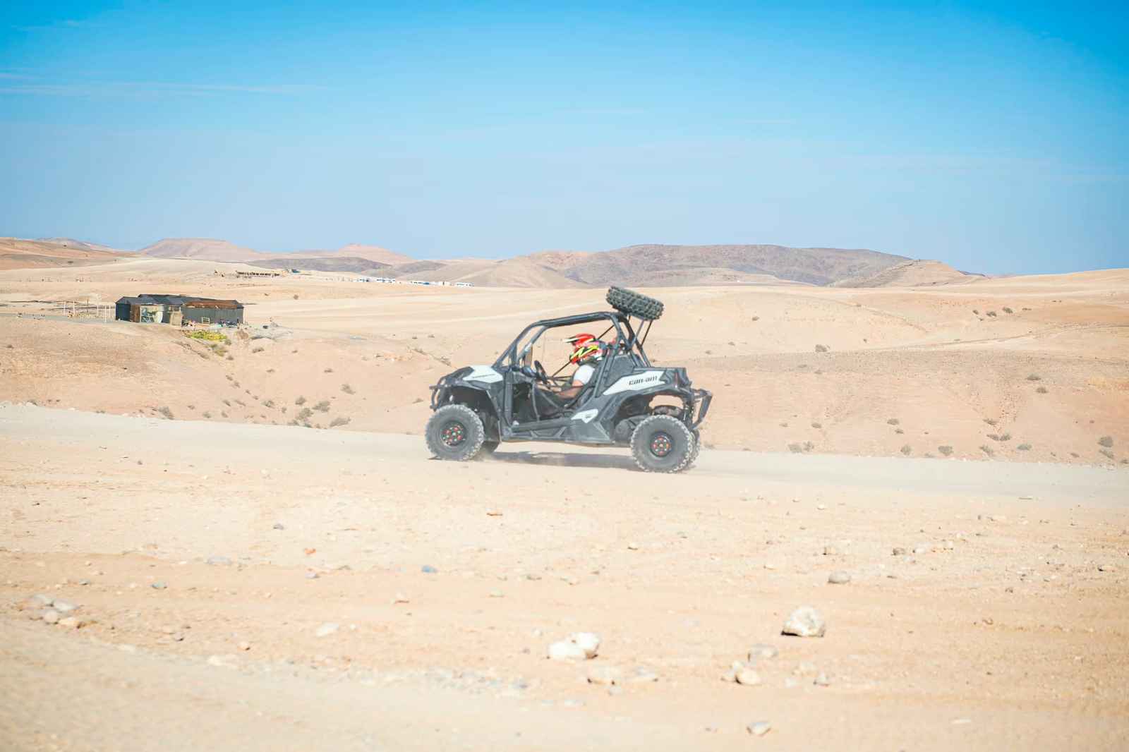 Black and white buggy in profile on a wide track, nomad tent and hills behind