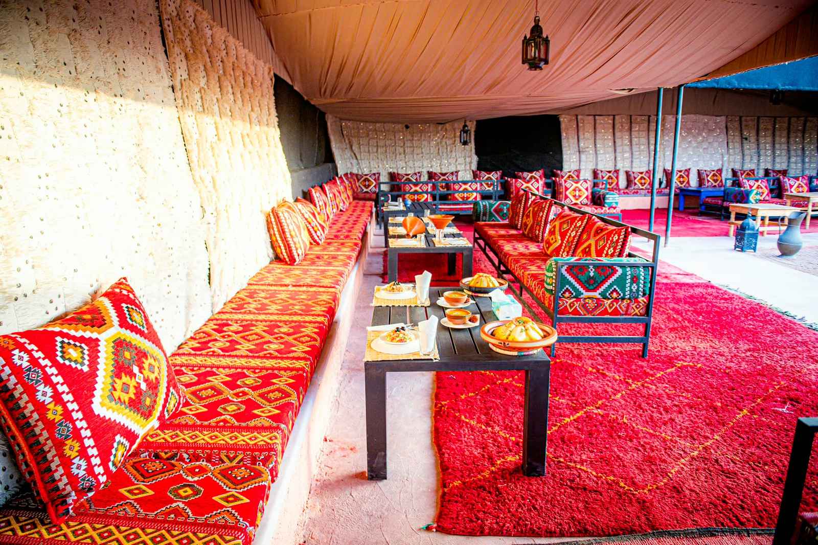 Dining tent, red rugs and cushions along the benches
