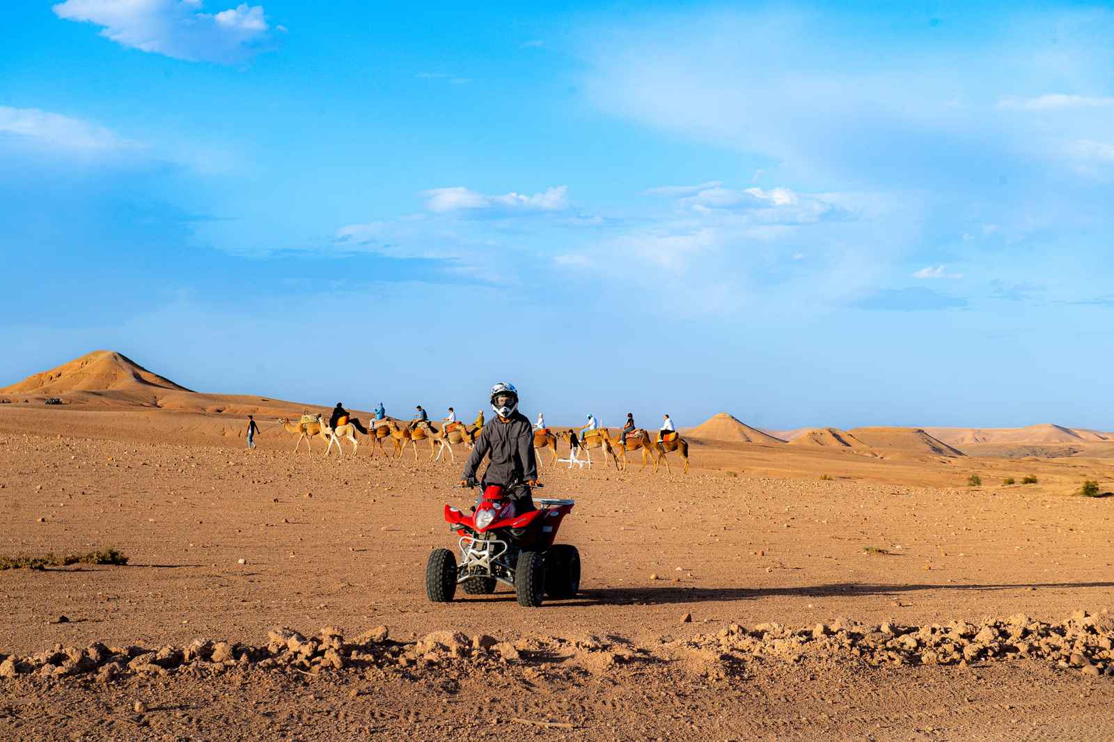 Lone rider on a red quad crossing a stony plain