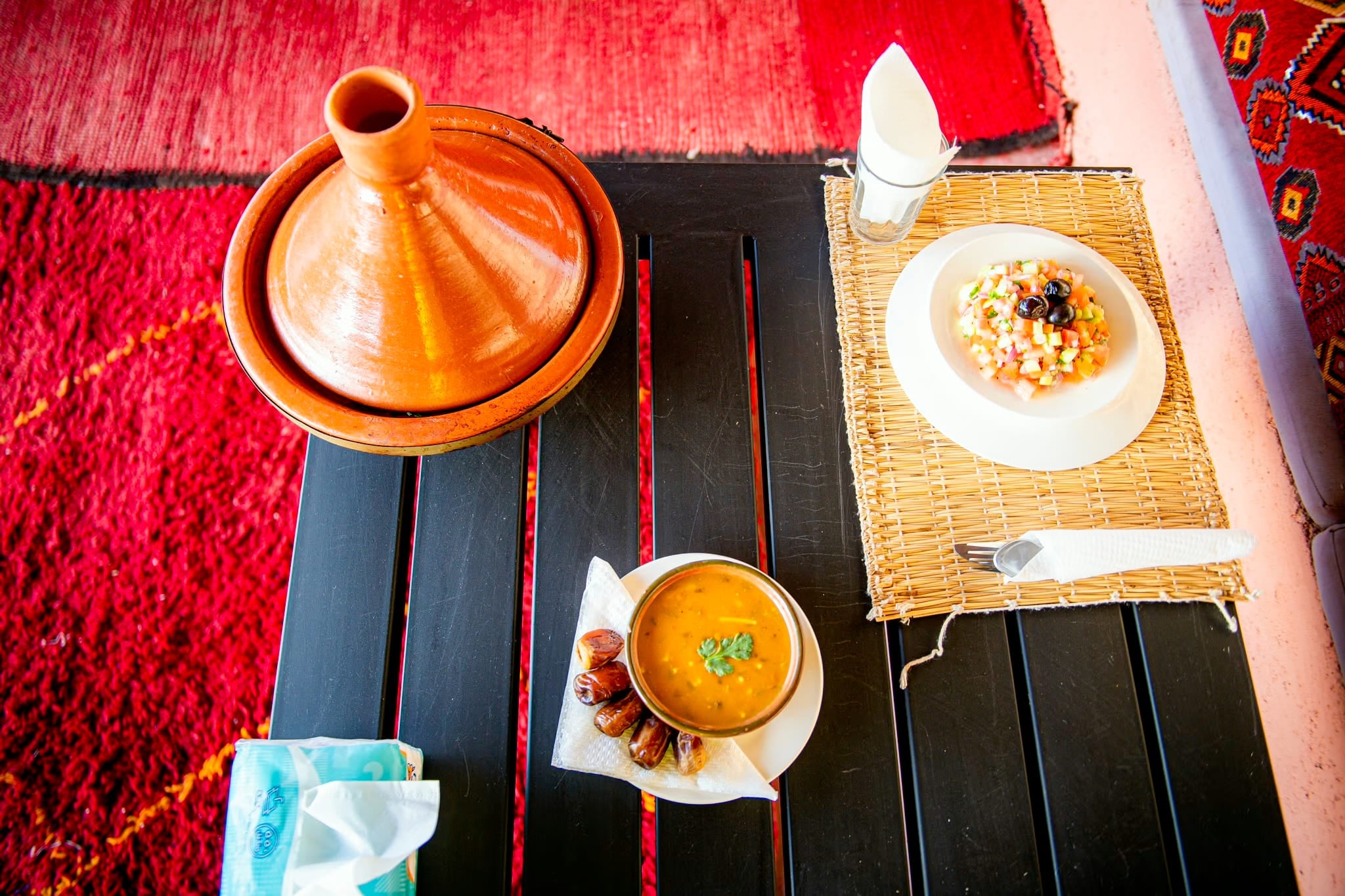Tajine, zuppa e insalata visti dall'alto su un tavolo scuro